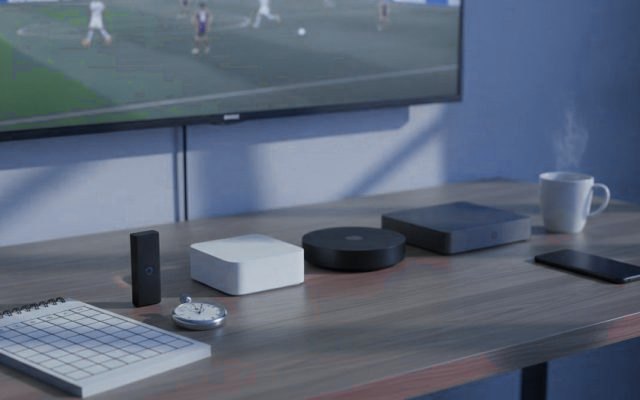 A notebook with a scoring grid, a stopwatch and several streaming devices laid out in front of a TV during a live match